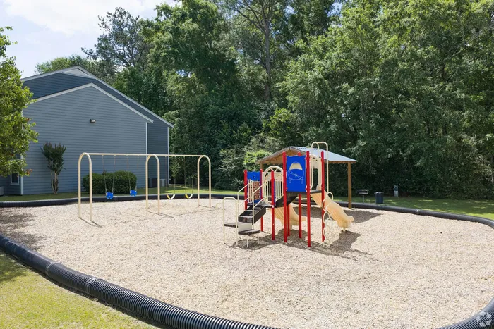Charming playground with vibrant slides and swings, surrounded by lush greenery, perfect for family fun and outdoor play.