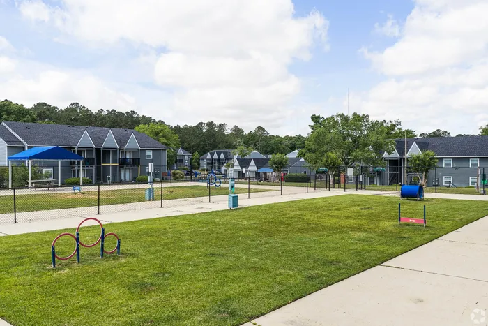 Charming apartment complex featuring blue-roofed buildings surrounded by lush greenery and an inviting playground area.