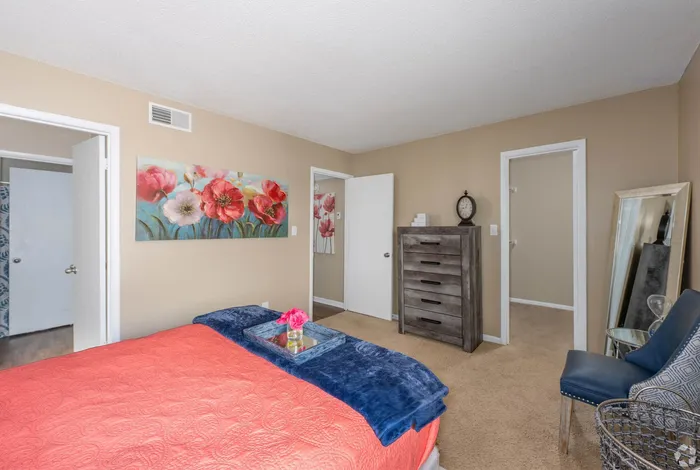 Cozy bedroom featuring a vibrant floral painting, elegant furniture, and a plush carpet creating a warm atmosphere.