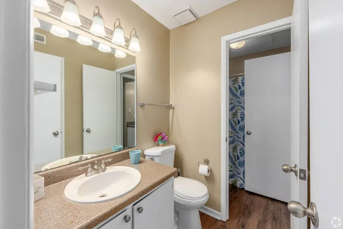 Bright and inviting bathroom featuring elegant lighting, a modern sink, and stylish decor with floral accents.