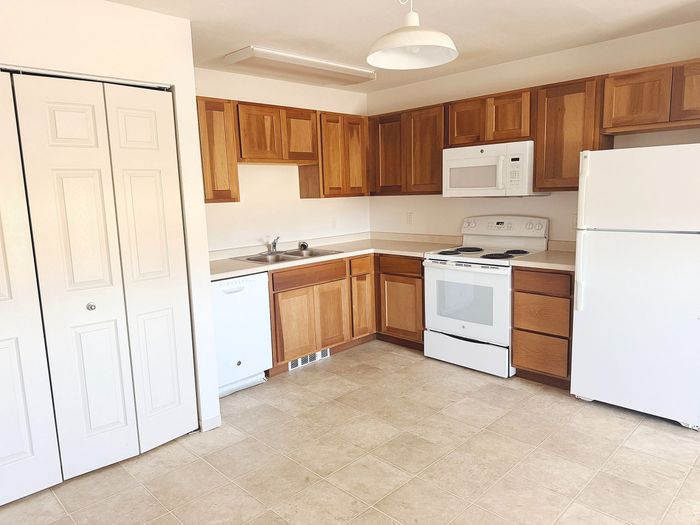 Bright and modern kitchen featuring warm wooden cabinets, white appliances, and ample storage space.