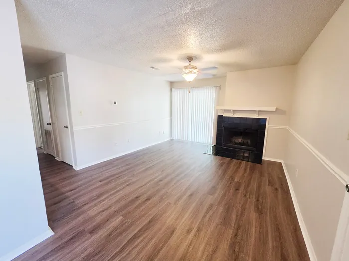 Inviting living room with elegant wood flooring, cozy fireplace, and abundant natural light from sliding glass doors.