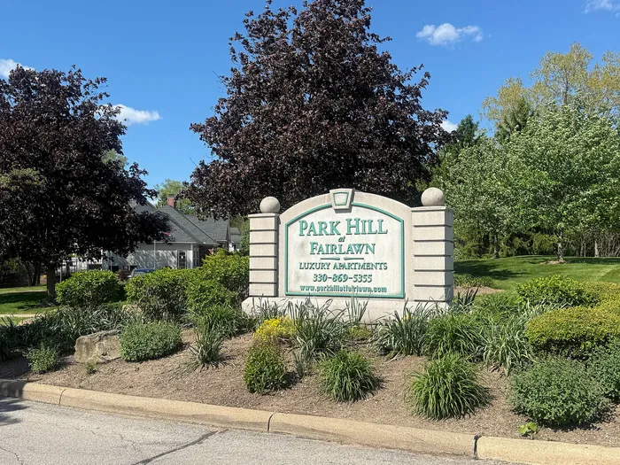 Inviting entrance sign for Park Hill at Fairlawn Luxury Apartments surrounded by lush greenery and tranquil landscaping.