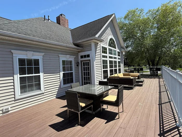 Charming outdoor patio featuring elegant wicker furniture and expansive deck space, perfect for relaxation and entertaining.