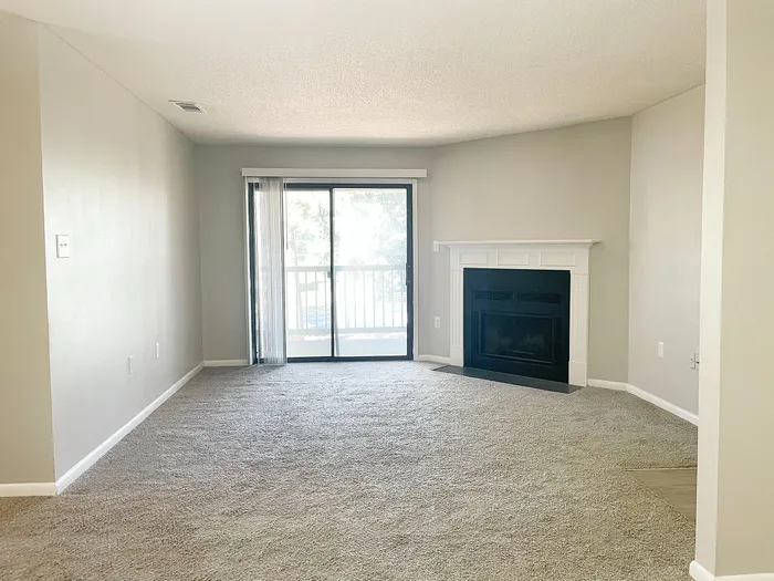 Bright living room with cozy fireplace and sliding glass doors leading to a private balcony.