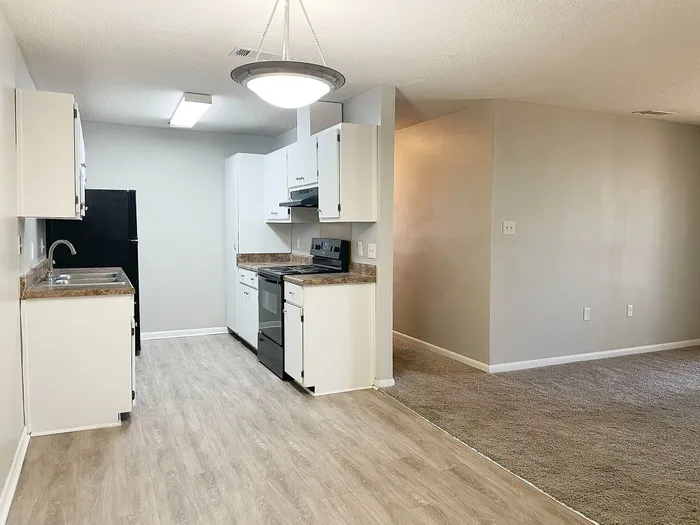 Bright and modern kitchen with sleek countertops, white cabinetry, and an open flow into a cozy living area, perfect for entertaining.