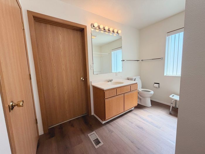 Bright and modern bathroom with elegant wood finishes, large mirror, and natural light.