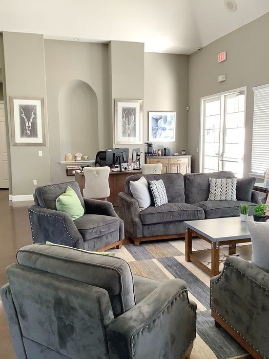 Inviting living room area featuring plush gray seating, modern decor, and abundant natural light from large windows.