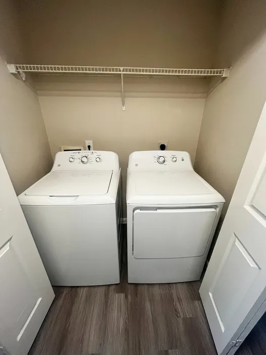 Modern laundry space featuring sleek white washer and dryer with ample shelving in a stylish apartment setting.