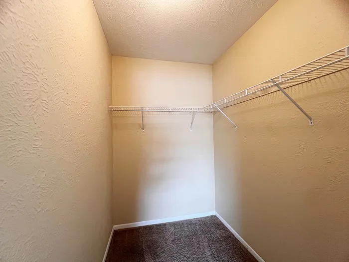 Spacious walk-in closet with elegant textured walls and ample shelving space.