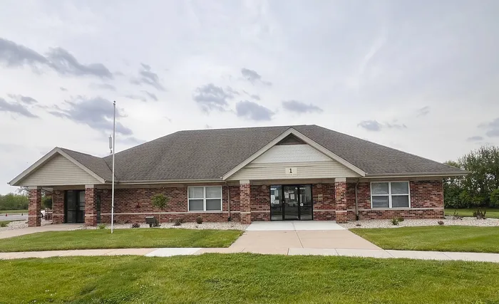 Charming brick building with a classic gable roof, surrounded by lush greenery and inviting walkways, ideal for versatile use.