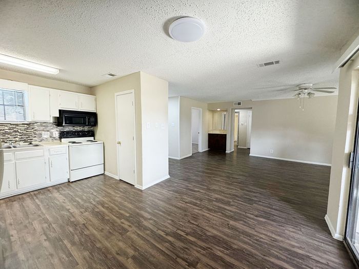 Modern open-concept apartment featuring a spacious living area, sleek kitchen with updated appliances, and elegant wood flooring.