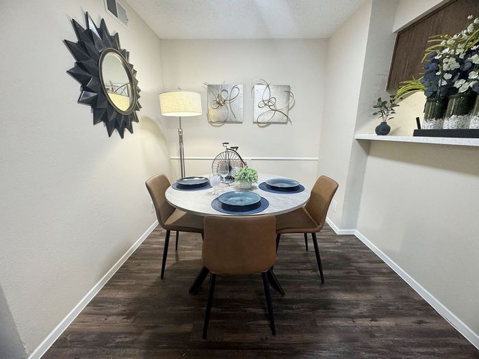 Chic dining nook with a round table set for four, accented by stylish decor, elegant artwork, and warm lighting.