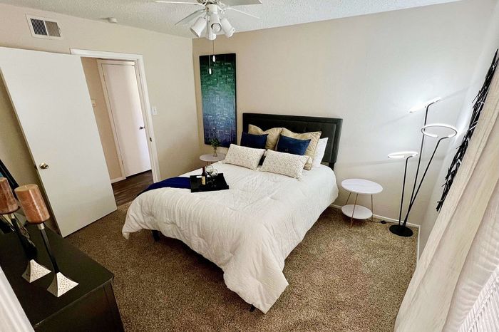 Cozy bedroom showcasing a plush bed with decorative pillows, elegant lighting, and modern artwork for a serene ambiance.