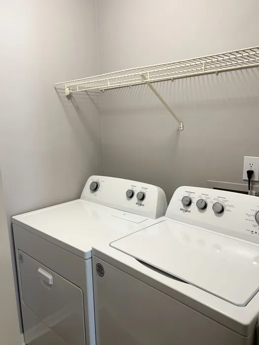 Modern laundry room with high-efficiency washer and dryer, featuring sleek design and ample shelving space.