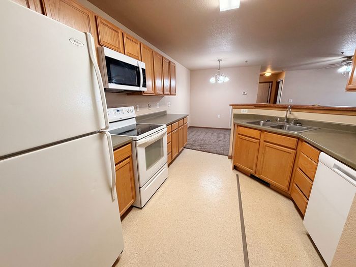 Modern kitchen with wooden cabinets, sleek countertops, and top appliances leading to a cozy dining area.