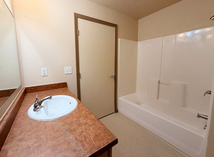 Inviting bathroom featuring a sleek sink with a modern faucet, spacious counter, and a pristine bathtub with chic finishes.