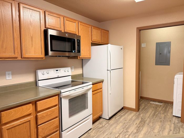 Inviting kitchen with warm wood cabinets, sleek stainless steel appliances, and stylish laminate flooring.
