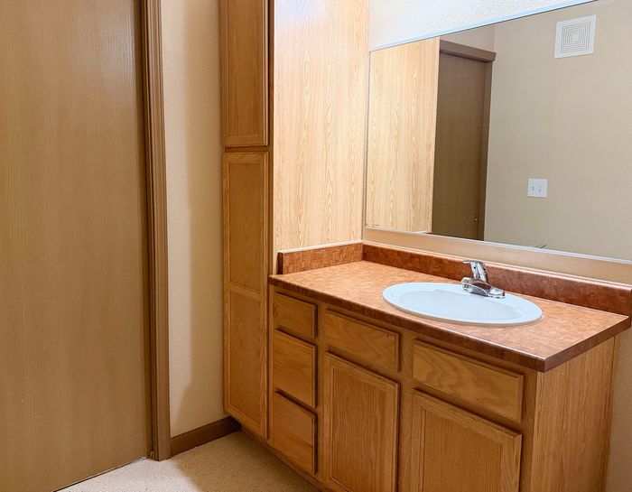 Bright and inviting bathroom with spacious wooden cabinetry and a sleek vanity mirror.