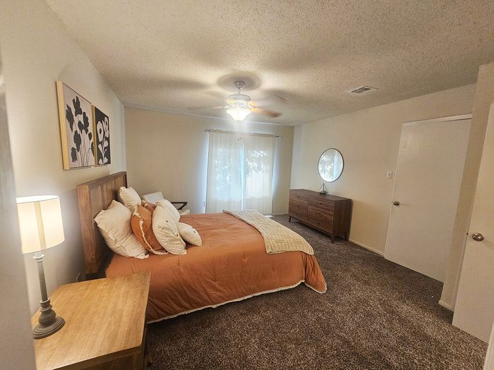 Inviting bedroom with warm tones, featuring plush bedding, cozy lighting, and stylish decor for a serene retreat.