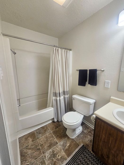 Modern bathroom with elegant tile flooring, a sleek vanity, and a stylish shower curtain.
