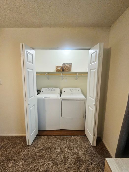 Convenient in-unit laundry with modern washer and dryer concealed behind elegant white folding doors.