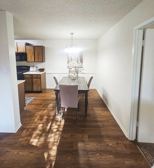 Inviting dining area with elegant chandelier lighting, wood floors, and a cozy kitchen nook featuring classic wood cabinetry.