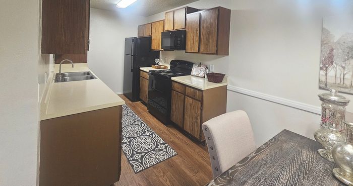 Charming kitchen with stylish wooden cabinets, sleek black appliances, and warm hardwood floors, perfect for inviting cozy gatherings.