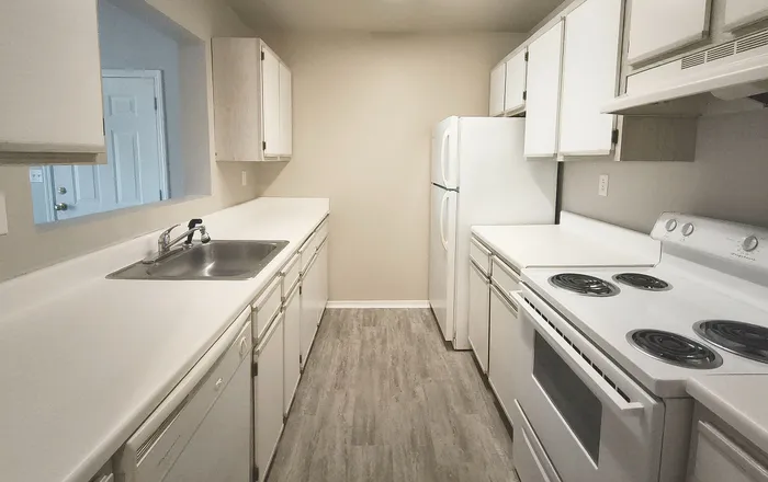 Modern galley kitchen featuring sleek white cabinets, ample countertop space, and contemporary appliances.