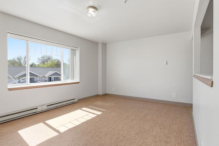 Bright, spacious room with large window, ample natural light, and elegant flooring, offering a serene and inviting atmosphere.