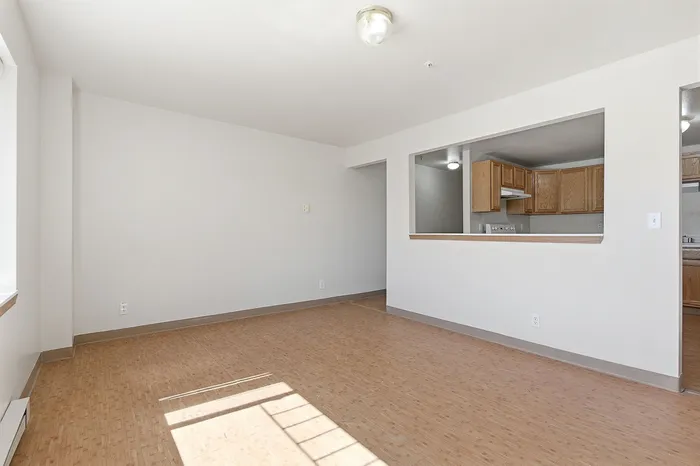 Bright open living area with natural light, featuring a cozy kitchen with wooden cabinetry and modern fixtures.