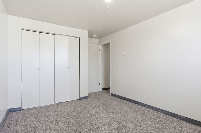Bright and inviting empty room with clean white walls, cozy carpet flooring, and a spacious closet, ready to be personalized in your new home.