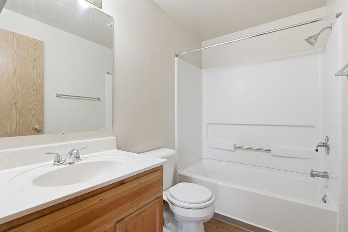 Bright and clean bathroom with an elegant white vanity, sleek sink, and a pristine shower and tub combination.