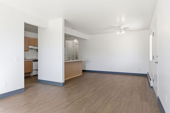Bright open-plan apartment with sleek hardwood floors, cozy kitchen, and modern lighting, perfect for stylish urban living.