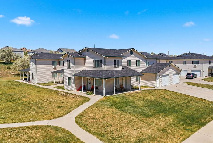 Charming duplex homes with inviting front porches in a peaceful neighborhood setting under a clear blue sky.