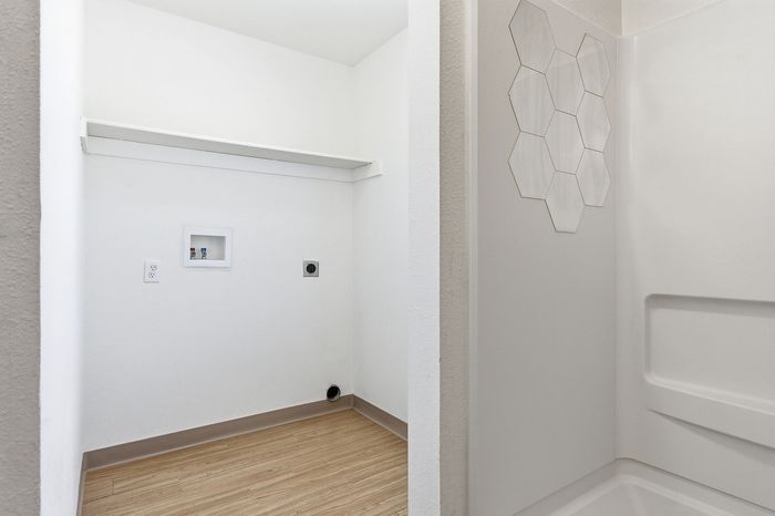 Bright utility space featuring convenient laundry hookups and stylish hexagon tile accent in an apartment setting.
