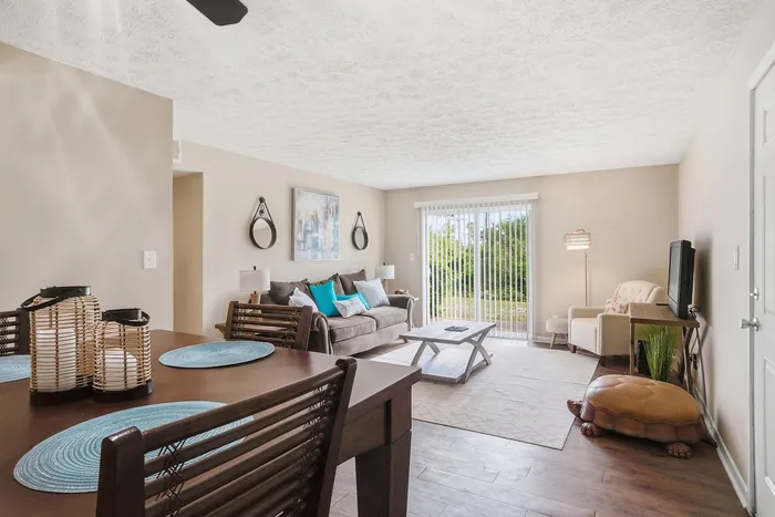 Inviting living room with stylish decor, cozy seating, and a view of the green outdoors through large glass doors.