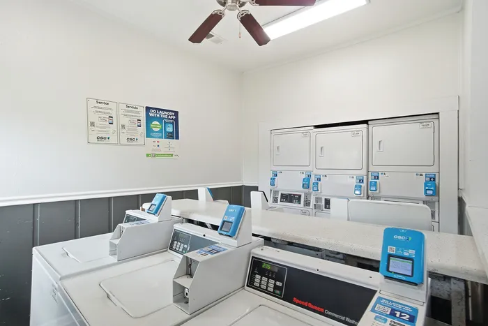 Modern laundry room equipped with advanced washers and dryers, featuring a bright and clean design with convenient payment options.