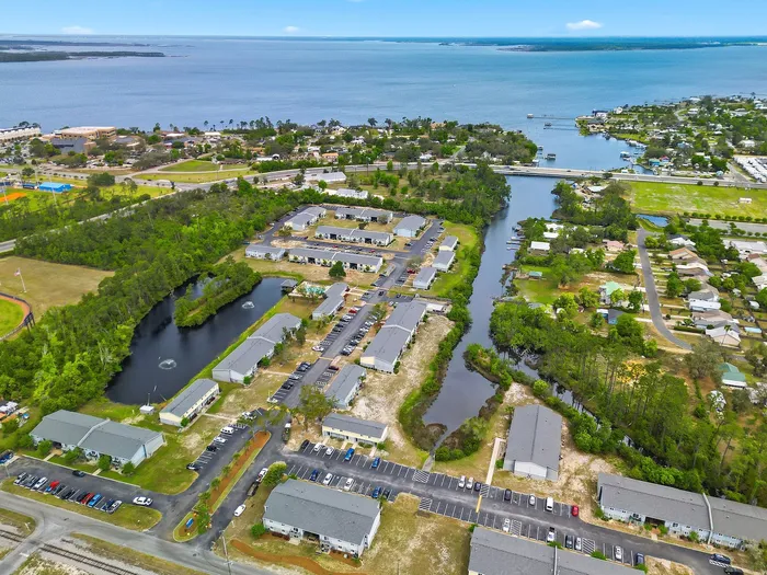 Aerial view of a serene waterfront community featuring stylish apartment complexes surrounded by lush greenery and scenic water channels.