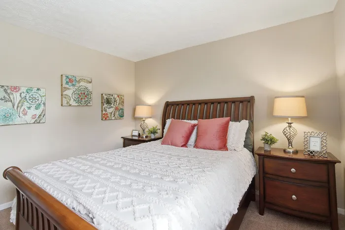 Inviting bedroom with elegant wooden furniture, vibrant artwork, and cozy lighting, perfect for relaxation.