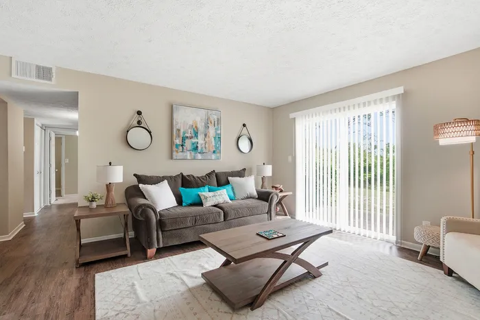 Bright and inviting living room featuring elegant decor, a cozy couch, and floor-to-ceiling windows with a lush garden view.