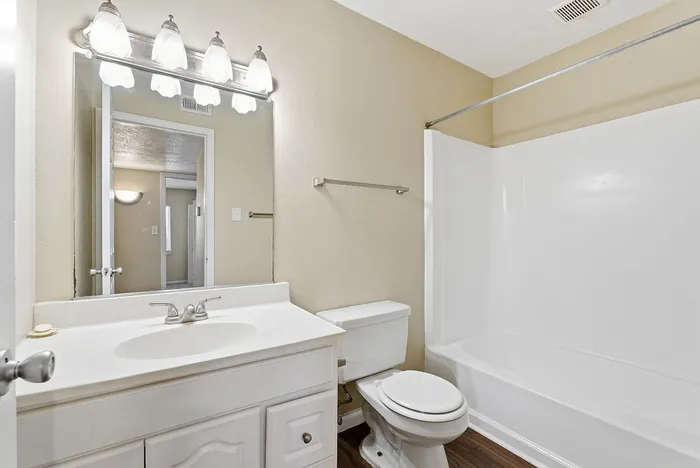 Bright and inviting bathroom with elegant lighting, pristine white fixtures, and a spacious bathtub.