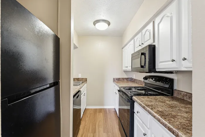 Modern kitchen with sleek black appliances, rich wood flooring, and ample countertop space for culinary creativity.