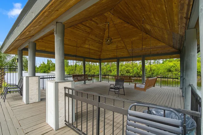 Charming lakeside gazebo with wooden swings and scenic surroundings, perfect for relaxation and enjoying nature.