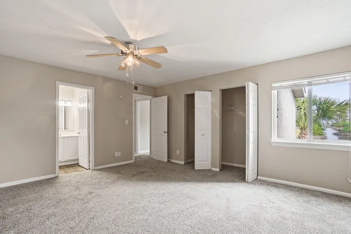 Inviting bedroom with plush carpet, ample closet space, and a serene window view.