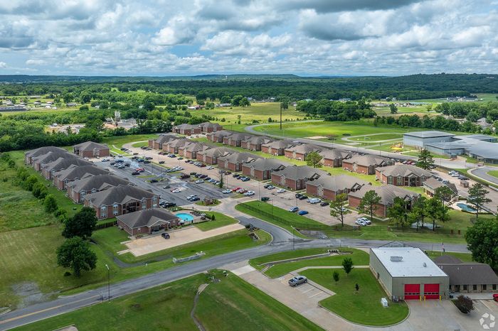 Scenic aerial view of a well-planned residential community with brick townhouses, lush green surroundings, and a sparkling pool.