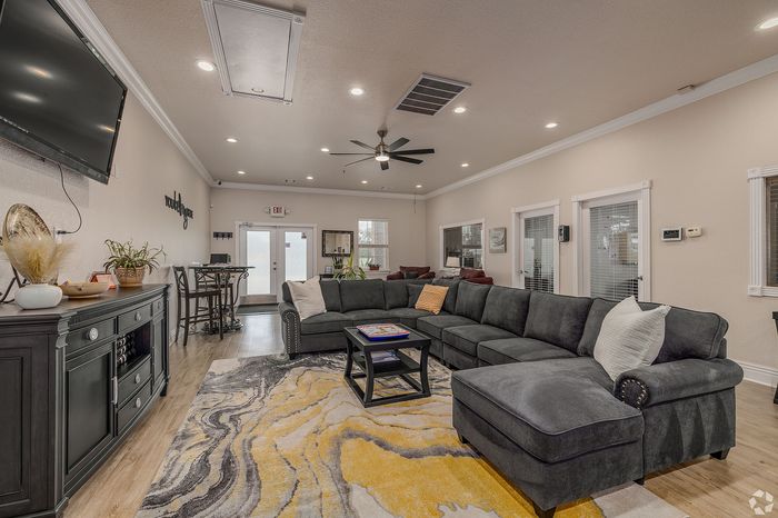 Chic and modern lounge area featuring a plush sectional sofa, vibrant abstract rug, and elegant decor with ample natural light.