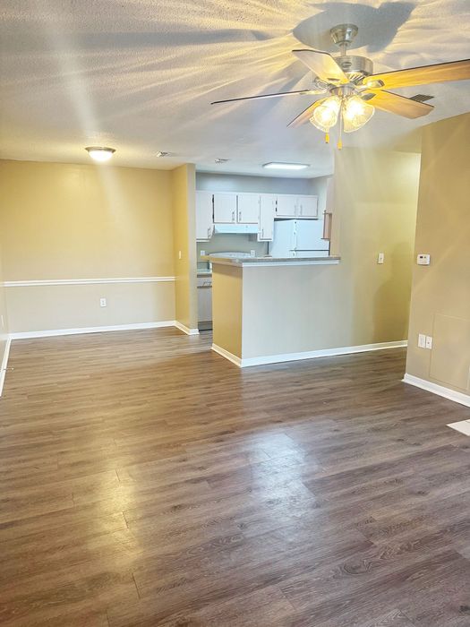 Inviting open-plan living area with elegant wood flooring and bright kitchen perfect for entertaining.