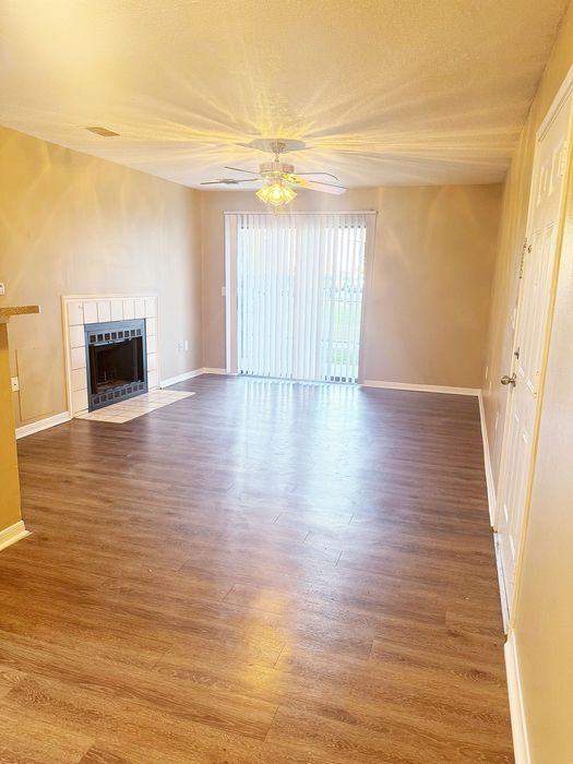 Bright living room with elegant wood flooring, a cozy fireplace, and large glass doors opening to natural light.