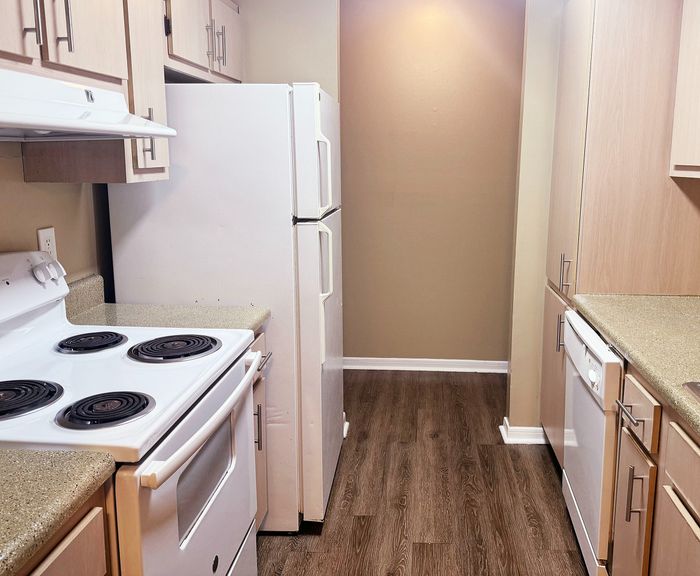 Modern kitchen with sleek appliances, warm wood cabinetry, and elegant countertops, offering a cozy and efficient culinary space.